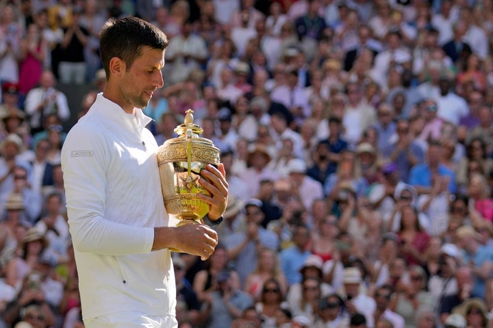 Serbia's Novak Djokovic holds the trophy as he celebrates after beating Australia's Nick Kyrgios to win the final of the men's singles on day fourteen of the Wimbledon tennis championships in London, Sunday, July 10, 2022. (AP Photo/Alastair Grant)