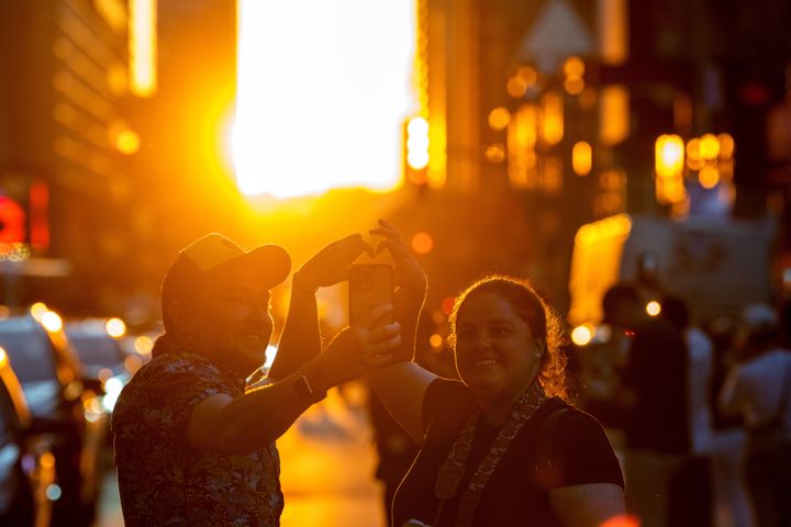 Οι άνθρωποι φτιάχνουν μια καρδιά με τα χέρια τους στην 42η οδό για να παρακολουθήσουν το ηλιοβασίλεμα κατά τη διάρκεια του Μανχάτανχεντζ στην Times Square στις 29 Μαΐου 2022 στη Νέα Υόρκη. (Photo by Alexi Rosenfeld/Getty Images)