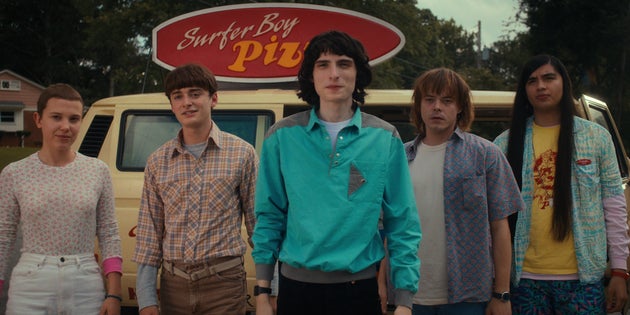 Stranger Things stars Millie Bobby Brown (Eleven), Noah Schnapp (Will Byers), Finn Wolfhard (Mike Wheeler), Charlie Heaton (Jonathan Byers) and Eduardo Franco (Argyle) stand in front of the Surfer Boy Pizza truck.