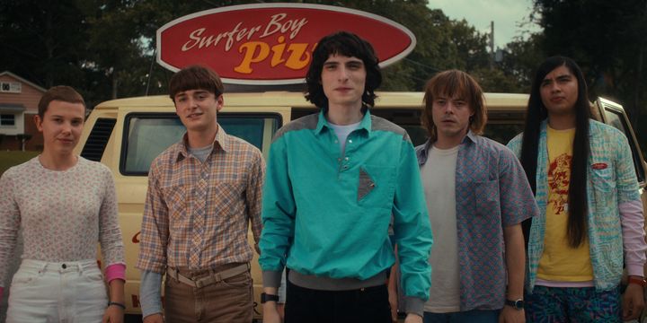 Stranger Things stars Millie Bobby Brown (Eleven), Noah Schnapp (Will Byers), Finn Wolfhard (Mike Wheeler), Charlie Heaton (Jonathan Byers) and Eduardo Franco (Argyle) stand in front of the Surfer Boy Pizza truck.