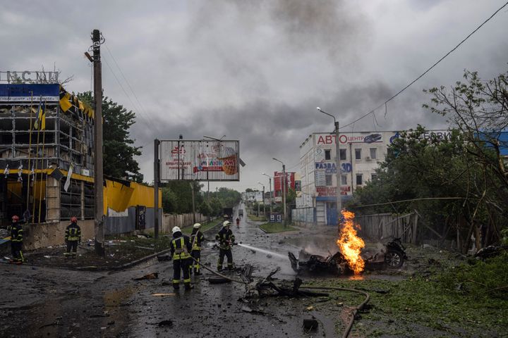 Rescue workers put out the fire of a destroyed car after a Russian attack in a residential neighborhood in downtown Kharkiv, Ukraine, on July 11, 2022. The top official in the Kharkiv region said Monday the Russian forces launched three missile strikes on the city targeting a school, a residential building and warehouse facilities.