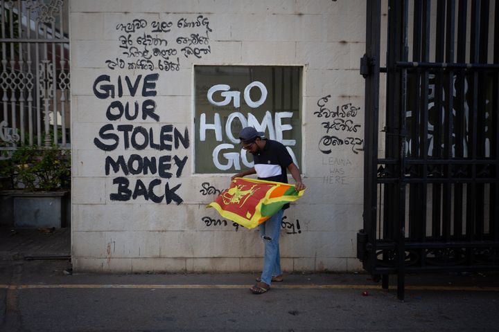 A protester unfurls the Sri Lankan national flag at the vandalized gateway of the presidential palace on July 13, 2022 in Colombo, Sri Lanka. Sri Lanka’s airforce has confirmed that President Gotabaya Rajapaksa has fled the country on a military jet to the Maldivian capital Male.