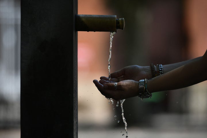Una persona intenta refrescarse bajo una fuente callejera