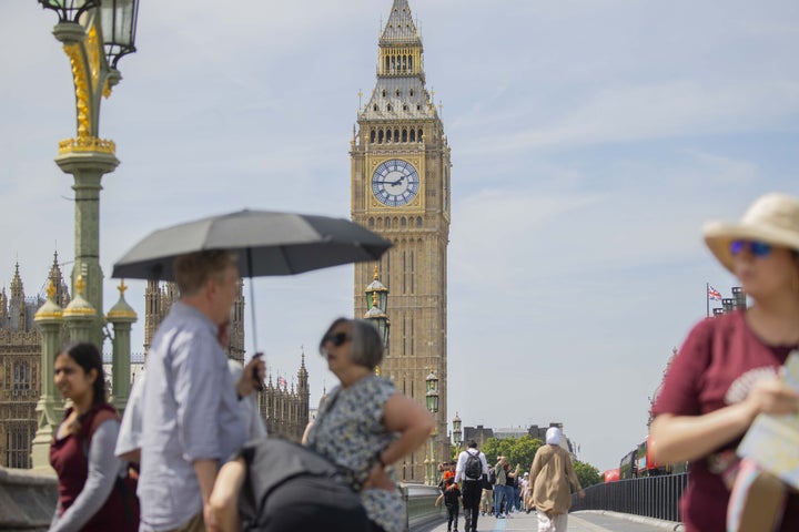 People walk through London with sun protection in mid-June, when temperatures soared past 90 degrees.