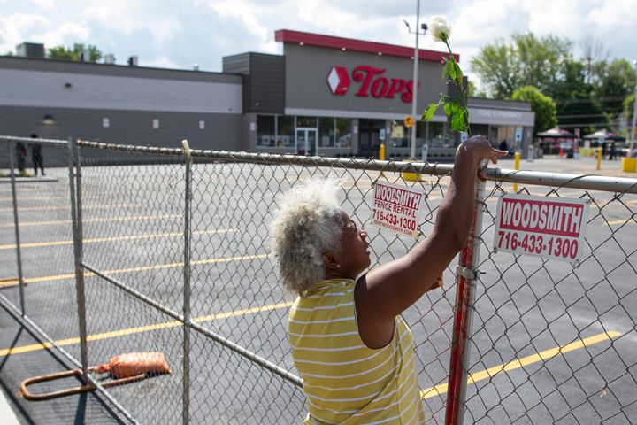 Cariol Horne, 54, places a rose on the fence outside the Tops Friendly Market on Thursday, July 14, 2022.