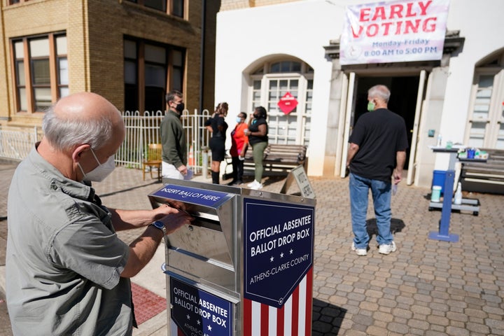 A voter submits a ballot in an official drop box during early voting in Athens, Ga., on Oct. 19, 2020. 