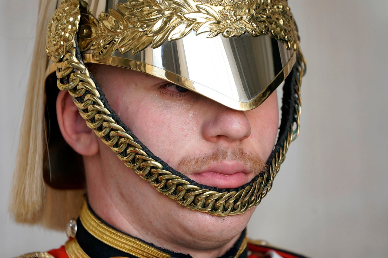 Sweat runs down the face of a member of the Household Troop at Horse Guards Parade in central London, Monday.