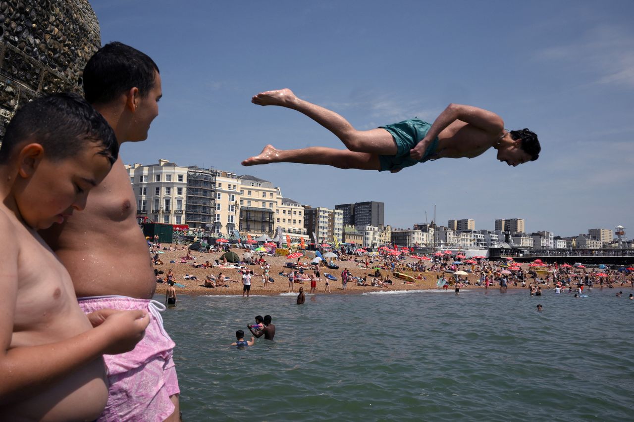 People jump from a rock into the sea at Brighton, southern England, on Sunday.