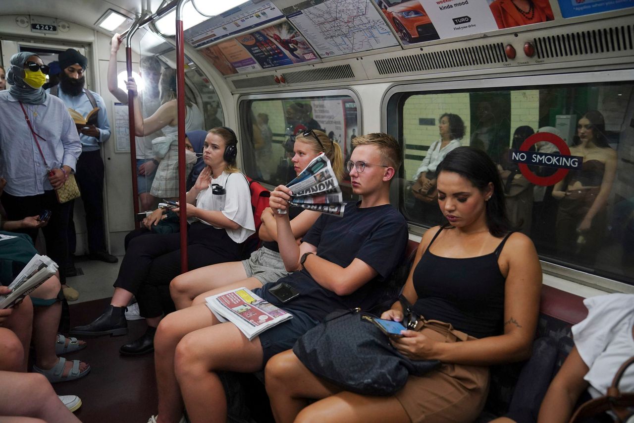 A man uses a newspaper as a fan while traveling on the Bakerloo line in central London during Monday's heat wave.