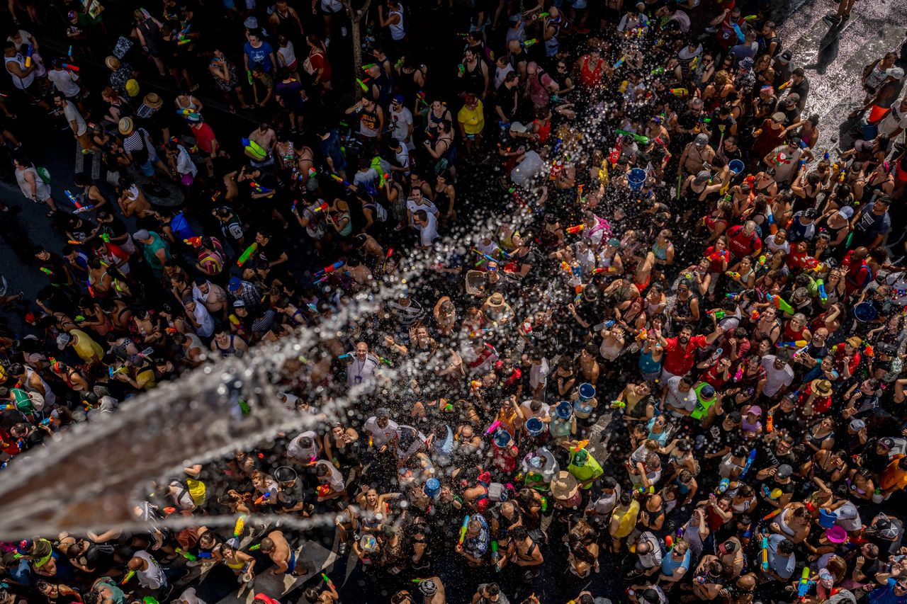 People throw water at each other during the annual water fight in the streets of the Vallecas neighborhood of Madrid, Spain, on Sunday.