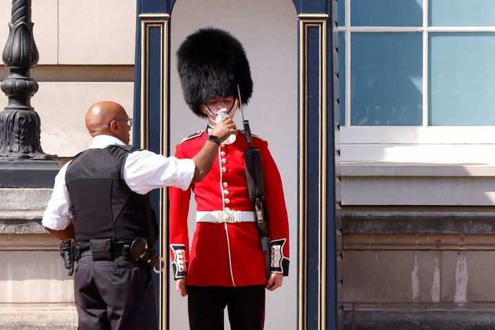 A member of the Queen's Guard receives water to drink during the hot weather, outside Buckingham Palace in London.
