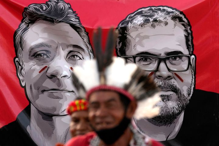 Indigenous men stand in front of images of slain British journalist Dom Phillips, left, and slain Indigenous expert Bruno Pereira in Brasilia, Brazil, on June 23.