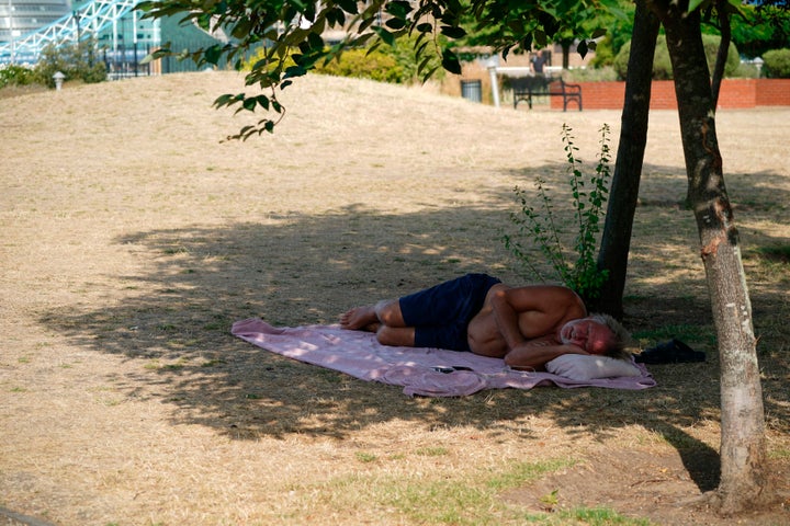 A man lays in the shade at a park in Wapping, east London, Tuesday July 19, 2022. (Yui Mok/PA via AP)