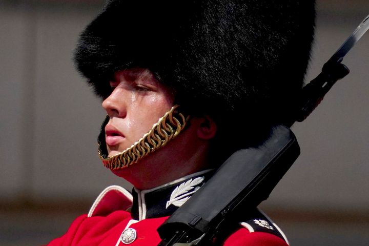 A member of F Company Scots Guards swelters in the heat during the Changing of the Guard ceremony on the forecourt of Buckingham Palace, central London, Tuesday July 19, 2022. (Victoria Jones/PA via AP)