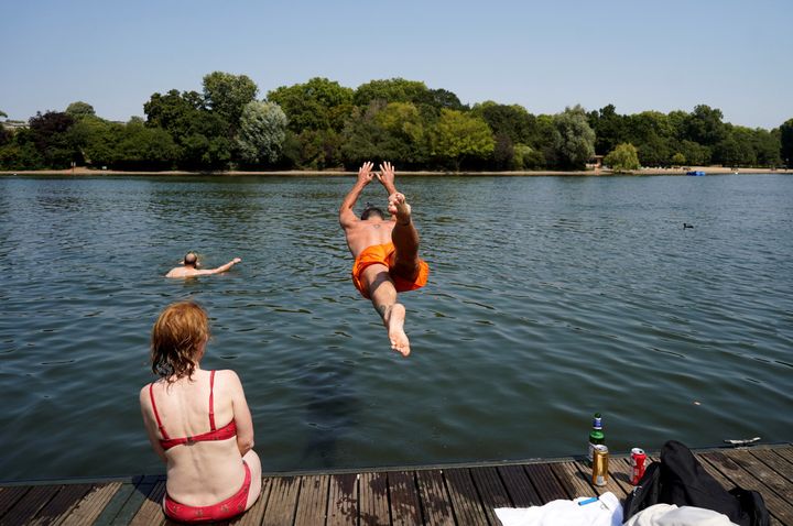 A man jumps into the Serpentine lake to cool off in Hyde Park, west London.
