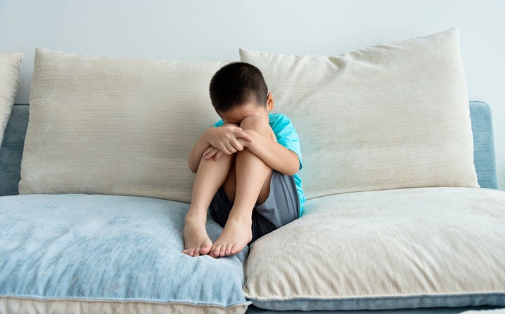 Sad boy sitting on sofa.