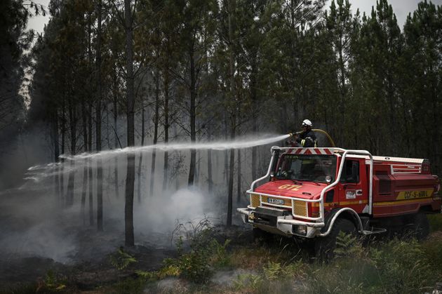 A firefighter sprays water as smoke rises at a forest fire near Louchats, 35 kms (22 miles) from Landiras in Gironde, southwestern France, Monday, July 18, 2022. France scrambled more water-bombing planes and hundreds more firefighters to combat spreading wildfires that were being fed Monday by hot swirling winds from a searing heat wave broiling much of Europe. With winds changing direction, authorities in southwestern France announced plans to evacuate more towns and move out 3,500 people at risk of finding themselves in the path of the raging flames. (Philippe Lopez/Pool Photo via AP)