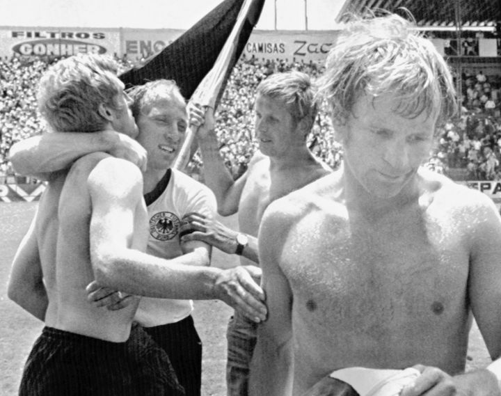 Ο αρχηγός της Δυτικής Γερμανίας Ούβε Ζέελερ (δεύτερος από αριστερά) αγκαλιάζει τον συμπαίκτη του Κλάους Φίχτελ μετά τη νίκη τους επί της Αγγλίας, στον προημιτελικό του Παγκοσμίου Κυπέλλου ποδοσφαίρου στη Λεόν του Μεξικό στις 14 Ιουνίου 1970. Ο Αγγλος Φράνσις Λι, δεξιά, φεύγει απογοητευμένος. Η Δυτική Γερμανία νίκησε την Αγγλία με 3-2 μετά την παράταση. (AP Photo/Lohmann)