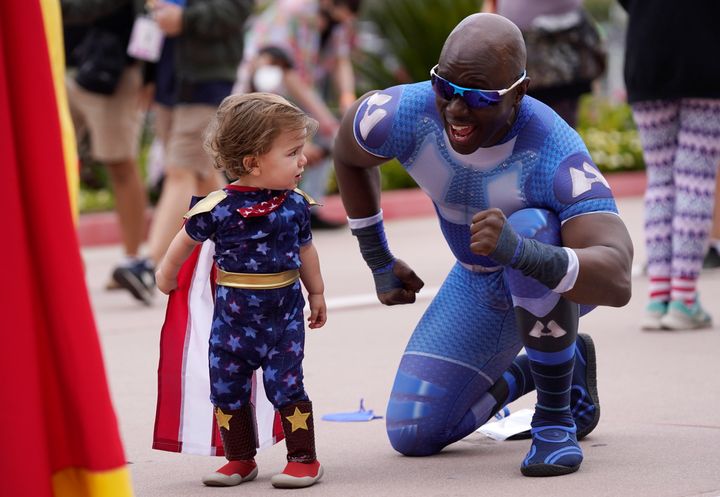 Jay Acey, right, dressed as A-Train from the television series "The Boys," mingles with Maddox Cruz, 1, of Orange, Calif., outside Preview Night at the 2022 Comic-Con International at the San Diego Convention Center.