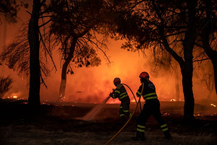 Bomberos en un incendio forestal que se acerca a una casa en El Hoyo de Pinares, en Ávila.