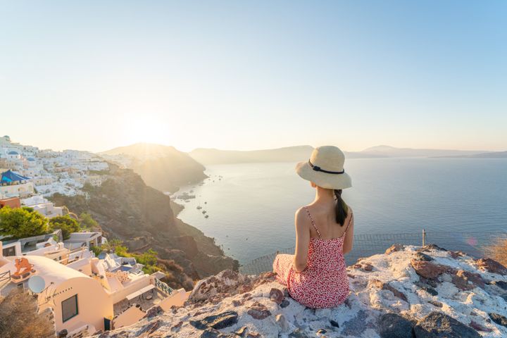 Una mujer viendo el atardecer en la isla de Santorini, Grecia.