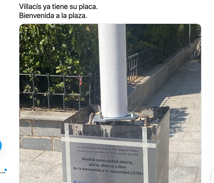 Placa bajo el mástil de la bandera LGTB en la plaza de Pedro Zerolo en Madrid.
