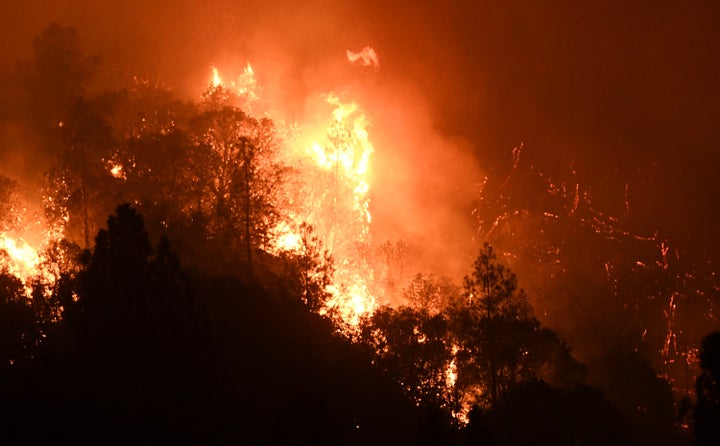 Tree canopies erupt into flame on a mountain side as a wildfire called the Oak Fire burns east of Midpines in Mariposa County, Calif., Friday, July 22, 2022.