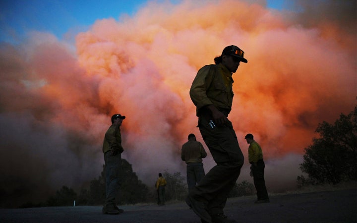 U.S. Forest firefighters stand along Triangle Road watching a wildfire called the Oak Fire burn east of Midpines in Mariposa County, Calif., Friday, July 22, 2022. The fast-moving wildfire near Yosemite National Park erupted Friday afternoon and prompted evacuations even as firefighters made progress against an earlier blaze that burned to the edge of a grove of giant sequoias. (Eric Paul Zamora/The Fresno Bee via AP)