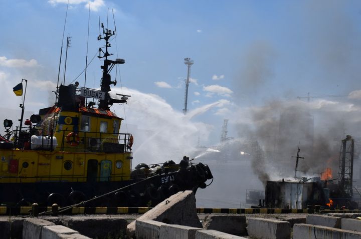 Πυροσβέστες παλεύουν με τις φλόγες μετά το χτύπημα ρωσικού πυραύλου στο λιμάνι της Οδησσού.