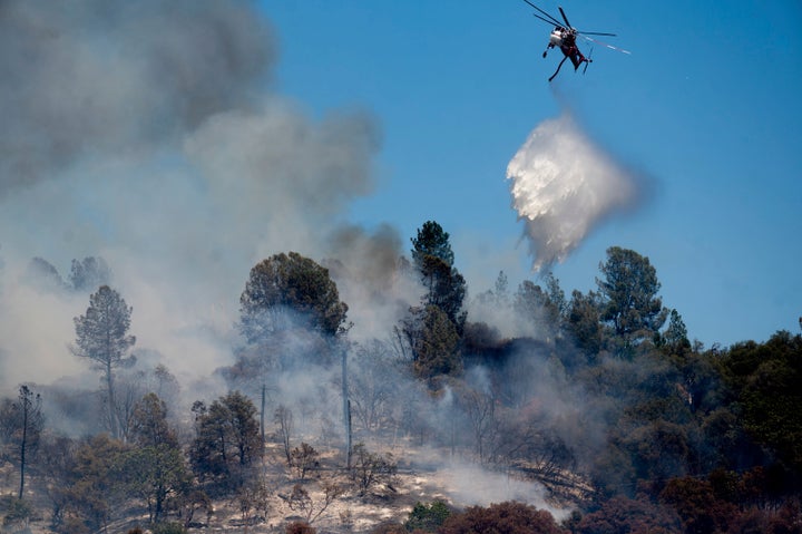 A helicopter drops water on the Oak Fire burning in Mariposa County, Calif., on Saturday, July 23, 2022. (AP Photo/Noah Berger)