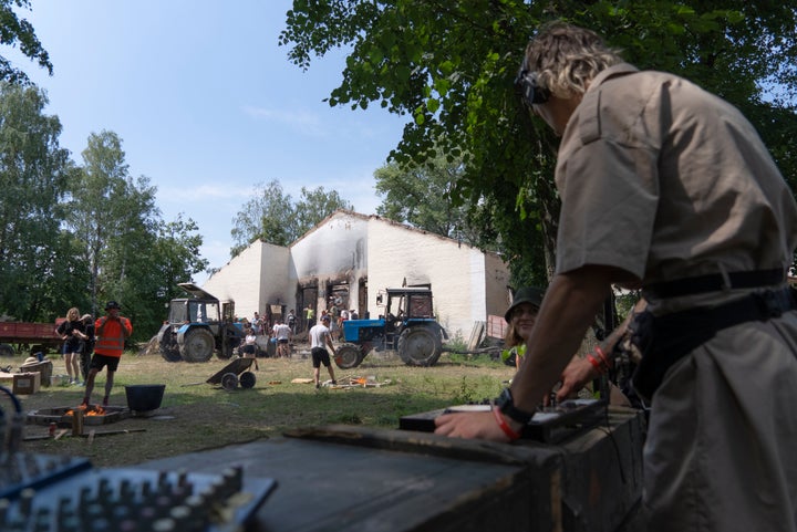 A DJ at work while young volunteers clear debris from a building destroyed by a Russian rocket in the village of Yahidne, Chernihiv Region, Ukraine, Sunday, July 24, 2022.