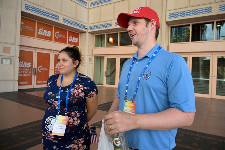 Ryan Malone, right, of Venice, Fla., and his wife, Mariuxi Viteri Malone, answer questions from a reporter outside the Tampa Convention Center during the Turning Point USA Student Action Summit, Saturday, July 23, 2022, in Tampa, Fla. (AP Photo/Phelan M. Ebenhack)