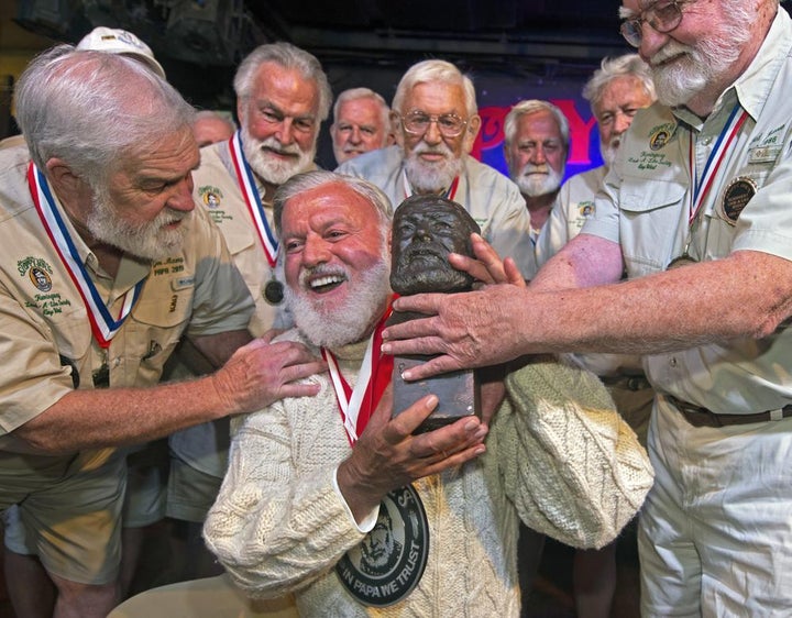 Jon Auvil, center, receives an Ernest Hemingway bust and congratulations after he won the 2022 Hemingway Look-Alike Contest at Sloppy Joe's Bar in Key West, Fla.