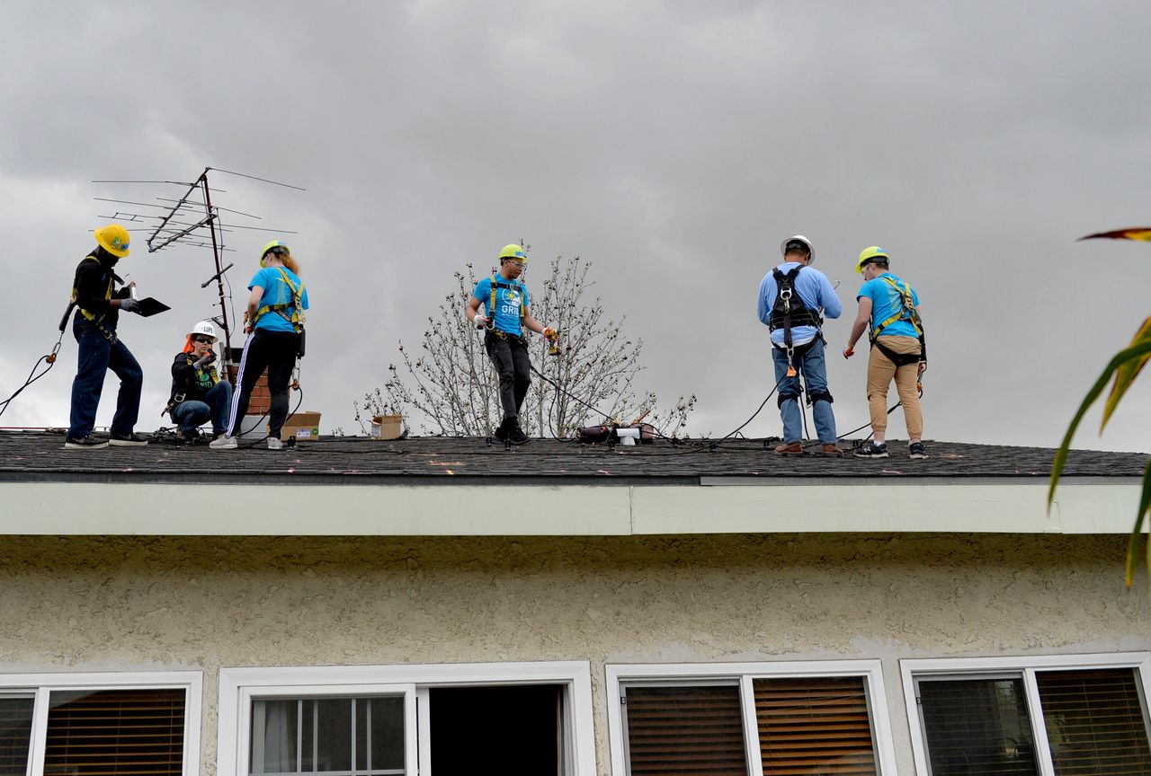 Students from the University of Michigan learn how to install a rooftop solar system at a home in Long Beach, California, in 2019. 