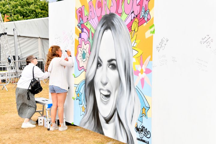 Guests write messages on a mural of Caroline Flack at Flackstock