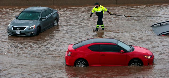 A tow truck driver moves to clear a flooded car as another rolls along Interstate 70 at Mid Rivers Mall Drive in St. Peters after heavy rain fell through Monday night and into the morning on Tuesday, July 26, 2022.