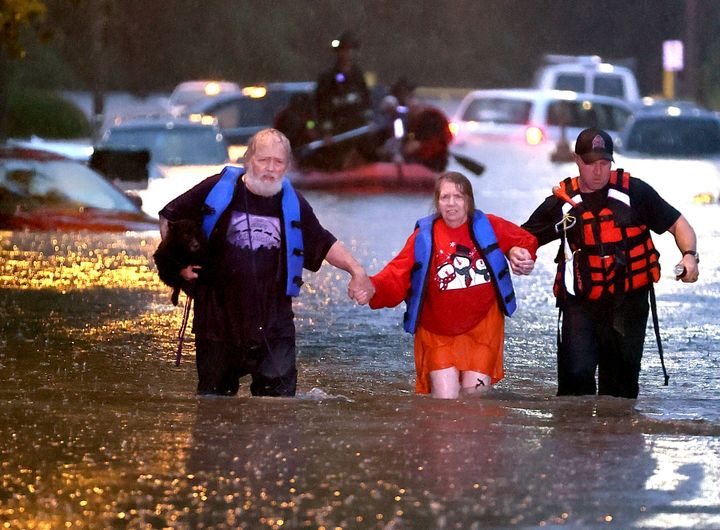 John Ward, left, and a firefighter help Lynn Hartke wade through the flash floodwater on Hermitage Avenue in St. Louis on Tuesday, July 26, 2022.