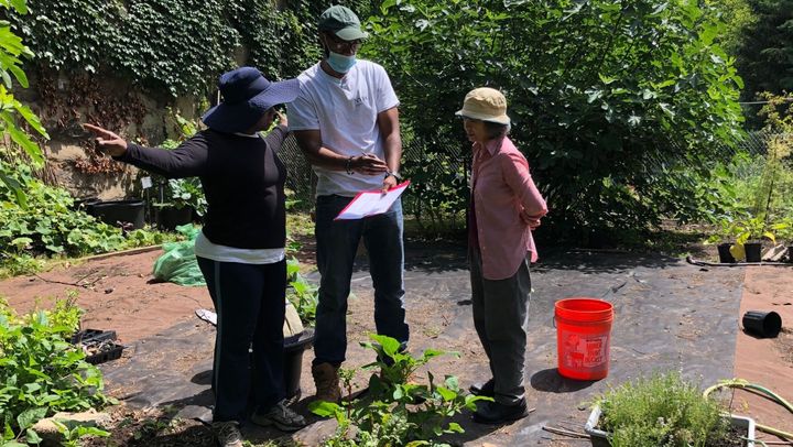 Che Cooper (center) works with community gardeners at the Giuseppe Garden in the Wakefield section of the Bronx to map out plans for an irrigation system.