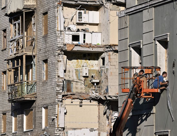 Workers cover shattered windows destroyed in an attack on residential building in central Kharkiv on Wednesday.