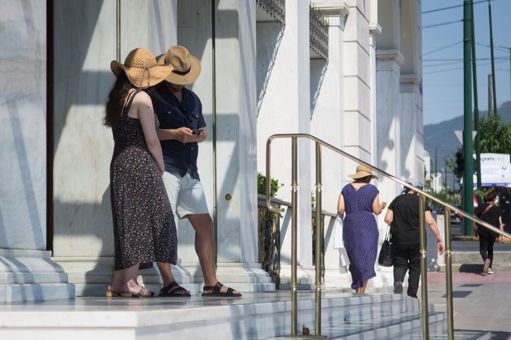 Τουρίστες με καπέλο έξω από το ξενοδοχείο Μεγάλη Βρεταννία στην πλατεία Συντάγματος κατά τη διάρκεια υψηλών θερμοκρασιών στην Αθήνα, Ελλάδα στις 17 Ιουλίου 2022. (Φωτογραφία Νικόλας Κοκοβλής/NurPhoto μέσω Getty Images)