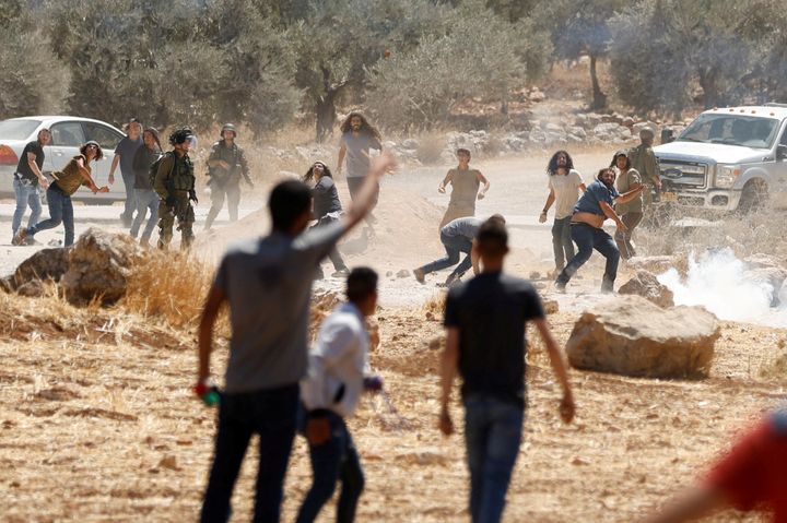 Παλαιστίνιοι διαδηλωτές συγκρούονται με Ισραηλινούς εποίκους κατά τη διάρκεια διαμαρτυρίας ενάντια στην ισραηλινή δραστηριότητα εποικισμού στο χωριό Al Mughayyir, στην κατεχόμενη από το Ισραήλ Δυτική Όχθη, 29 Ιουλίου 2022.