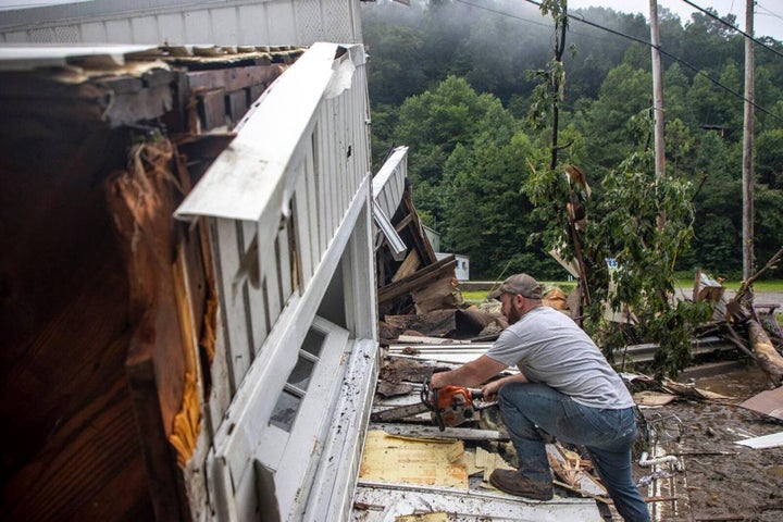 Sammy Gibson uses a chainsaw to cut apart a house that came to rest on a bridge near the Whitesburg Recycling Center in Letcher County, Kentucky, on July 29.