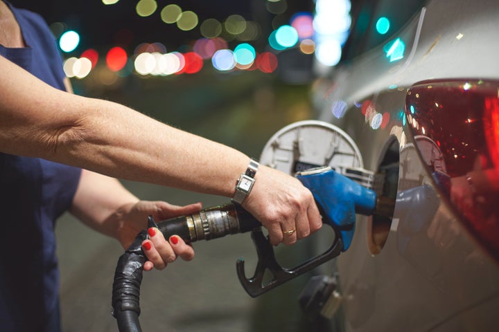 Close-up of hand of woman fueling up her car at the gas station by night