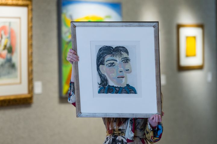 A staff member holds an aquatint and drypoint in colors titled "âTete de femme No 2. Portrait de Dora Maarâ" (1939) by Pablo Picasso at Bonhams auction house in London on May 16, 2022. 
