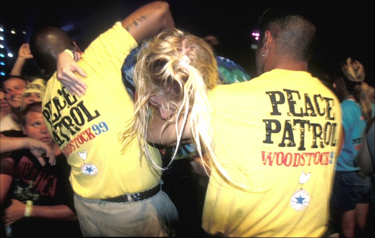 A young woman is pulled out of a violent crowd at Woodstock '99 by festival security.