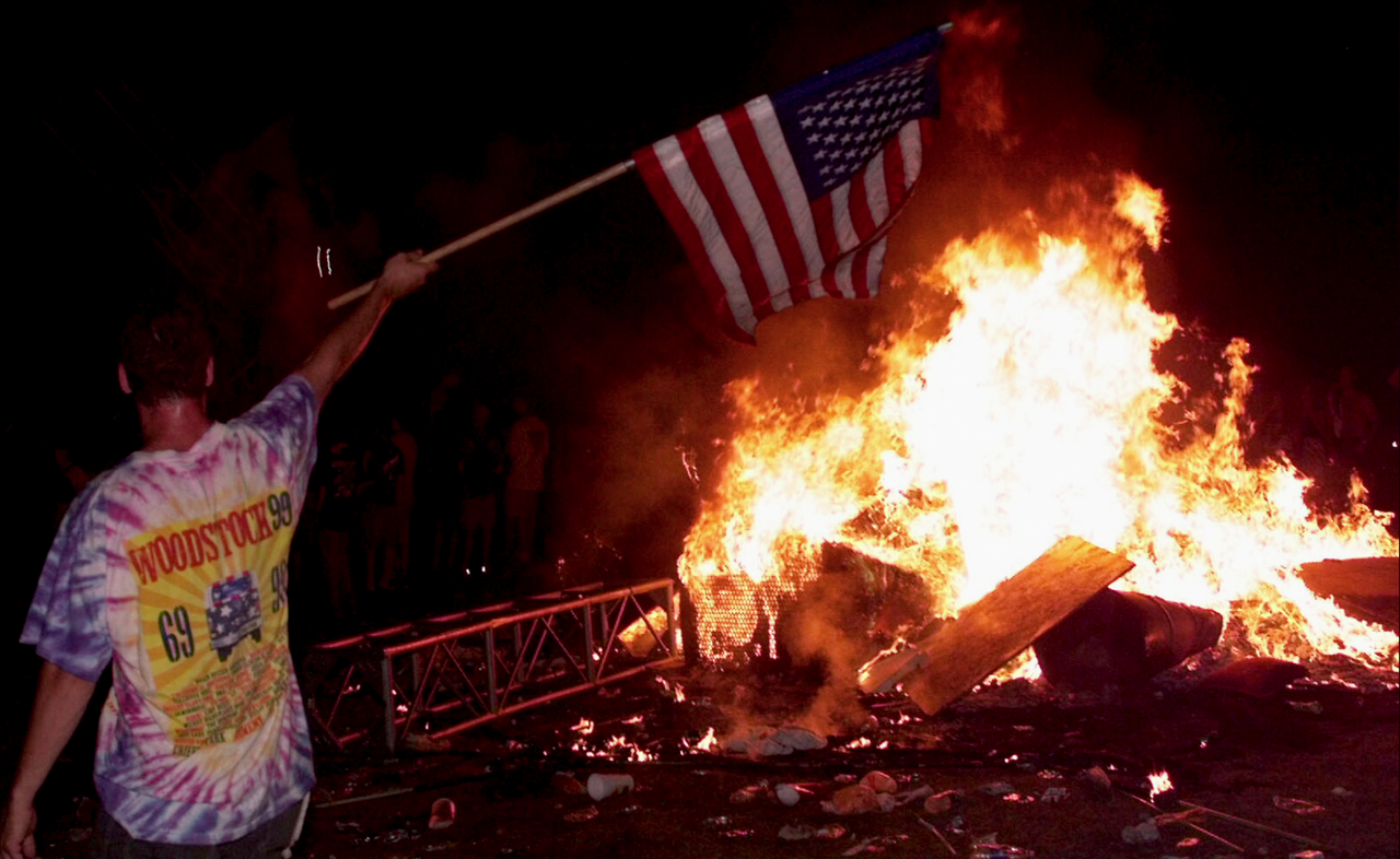 A young man waves the American flag in the midst of wreckage at Woodstock '99.