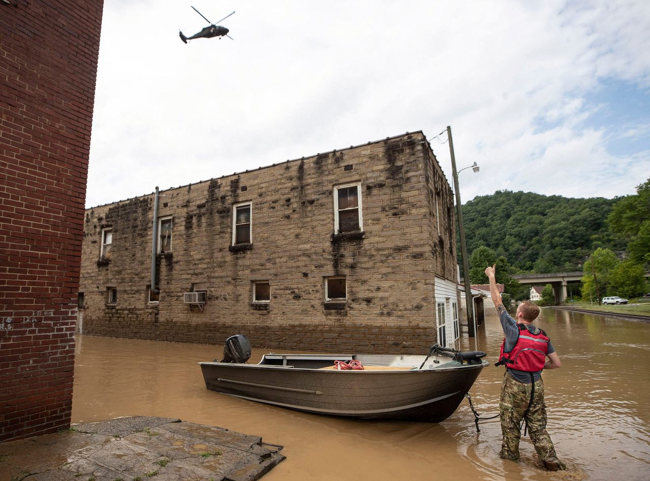James Jacobs signals to a National Guard helicopter flying overhead, following a day of heavy rain in in Garrett, Kentucky, on July 28.