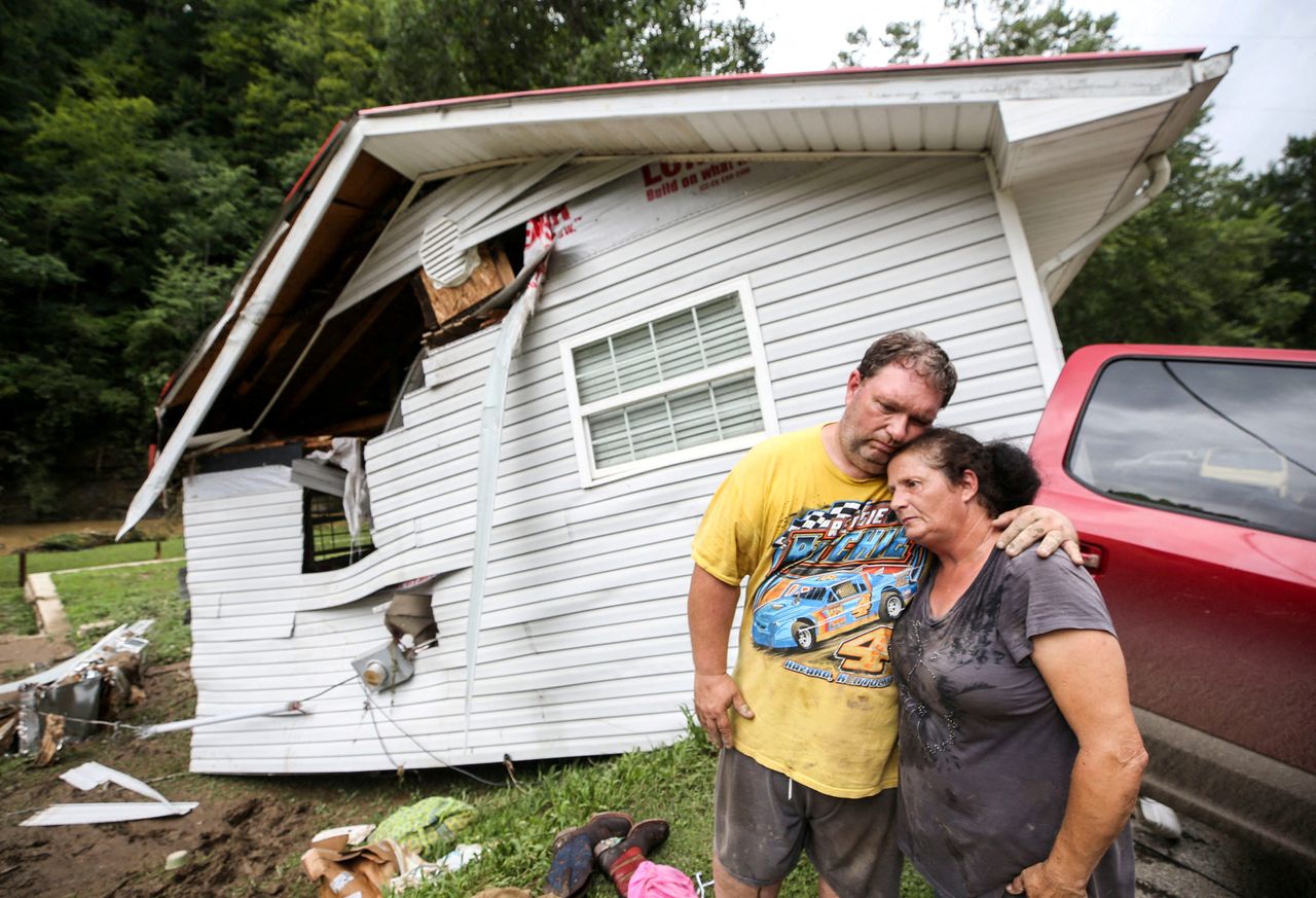 Reggie Ritchie comforts wife Della as they pause while clearing out their destroyed manufactured home destroyed by the flooding from Troublesome Creek behind them in Fisty, Kentucky, on July 29.