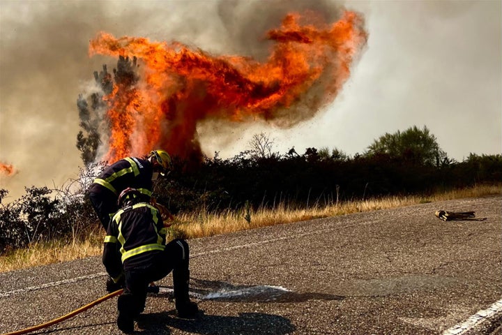 Efectivos de bomberos trabajan el domingo en la extinción de un incendio forestal en la carretera N120, en A Cañiza (Pontevedra).