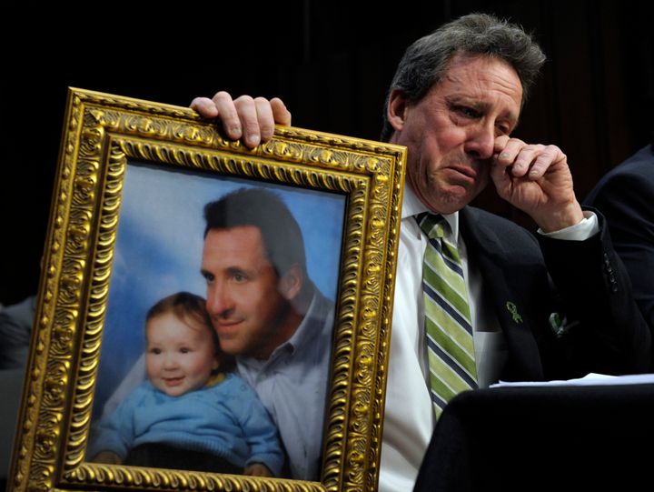 Neil Heslin, the father of Jesse, 6, who was killed in the Sandy Hook massacre in Newtown, Connecticut, holds a picture of them together as he wipes his eye while testifying before the Senate Judiciary Committee as it considered an assault weapon ban on Feb. 27, 2013.